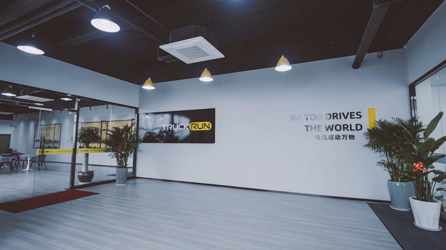 Modern office reception area with glass walls and plants.