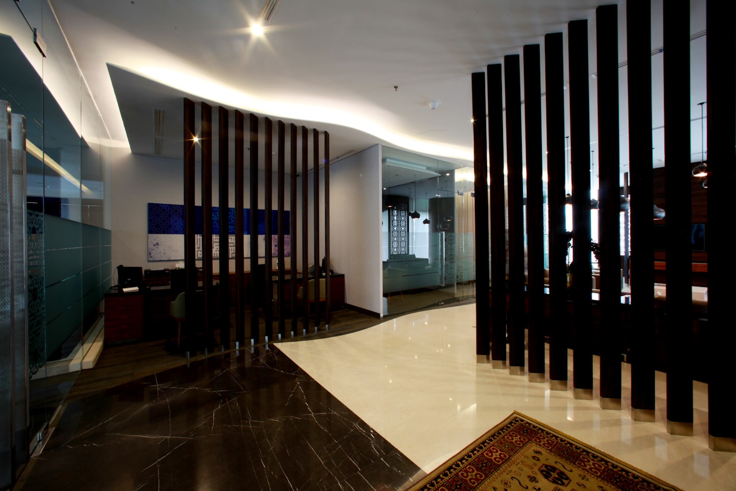 Modern office reception area with marble floors and wood partitions.