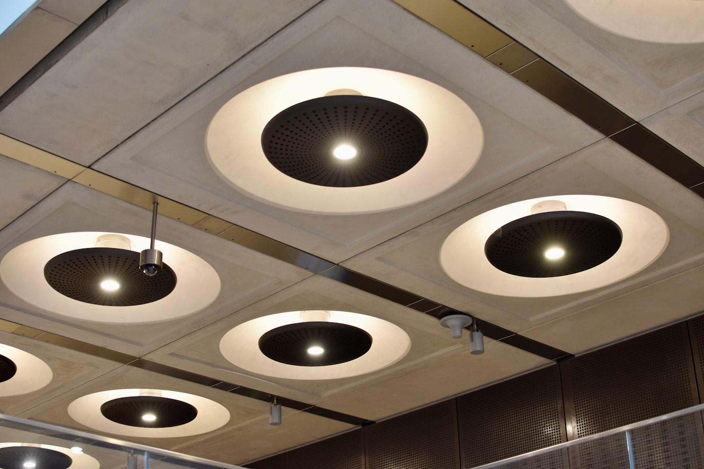 Modern ceiling grid with integrated circular lights and security camera.